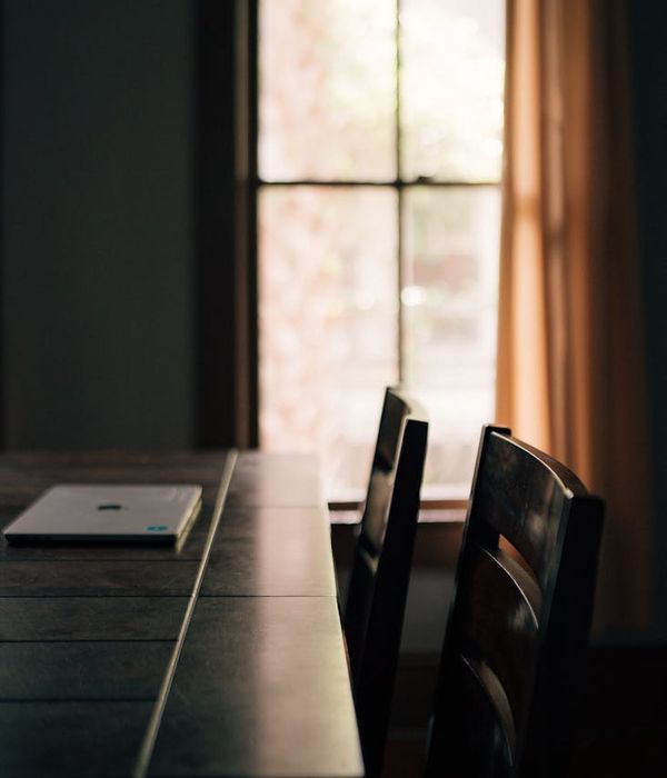 A tranquil, minimalist room with a comfortable chair and soft, natural light coming from a window.